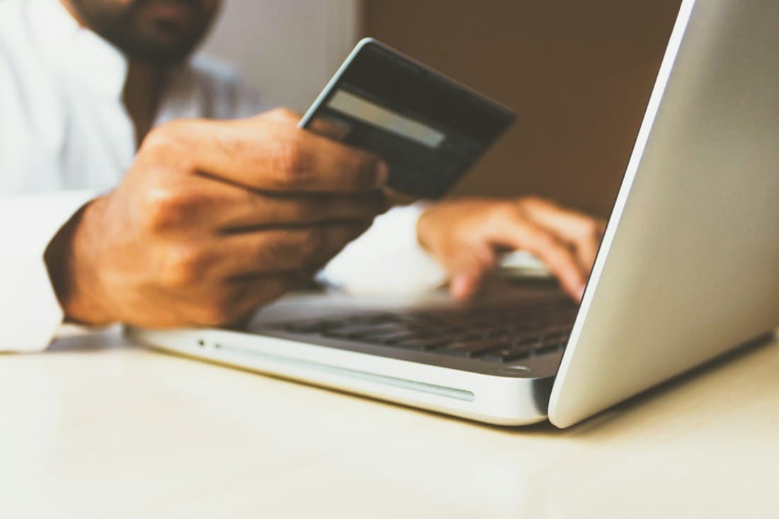 Person holding a card while using a laptop